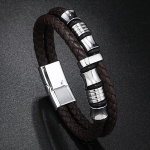 Gros plan d'un bracelet en cuir tressé pour homme avec breloques argentées et fermoir aimanté