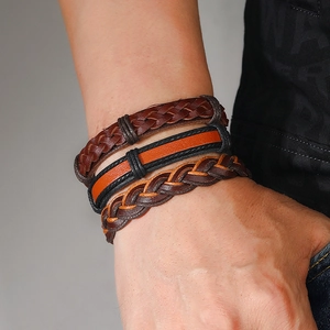 Close-up of triple-layered woven leather bracelets in coffee, orange, and black on a wrist