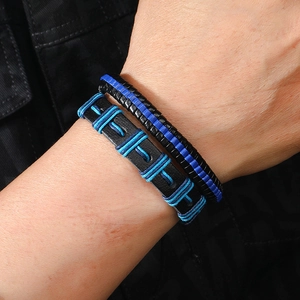 Detail of men's multilayered black and royal blue braided leather bracelets on a wrist