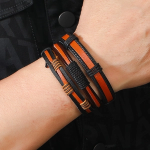 Dettaglio del set di tre bracciali in pelle intrecciata nera e arancione stile punk