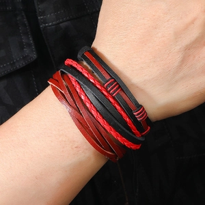 Detail of multi-layer handmade braided leather bracelets with red accents on model wrist