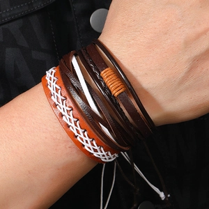 Detail of handmade vintage leather bracelets with white cross-stitching and woven cords