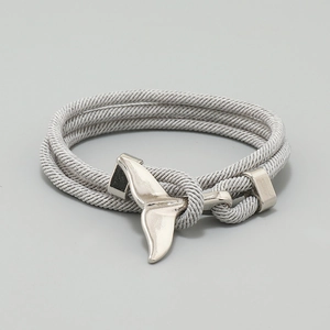 Macro shot of silver whale tail charm and grey woven cord of this nautical bracelet