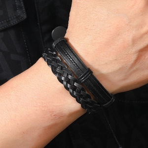 Detail of layered black braided leather bracelets with embossed patterns for men