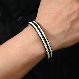 Detailed close-up of woven black and white leather bracelet with V-shape geometric pattern
