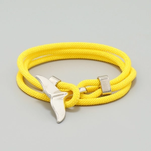 Detail of bright yellow woven nautical bracelet with polished whale tail metal charm