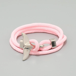 Detail of pink hand-woven nautical bracelet with a silver whale tail charm detail