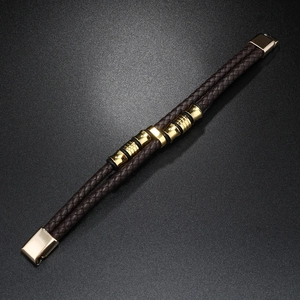 Détail d'un bracelet multicouche en cuir tressé marron avec fermoir magnétique doré