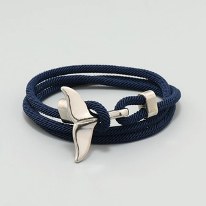Detail of dark blue nylon braided rope bracelet with silver whale tail charm clasp