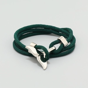 Close-up of deep green braided nautical bracelet with polished silver whale tail clasp
