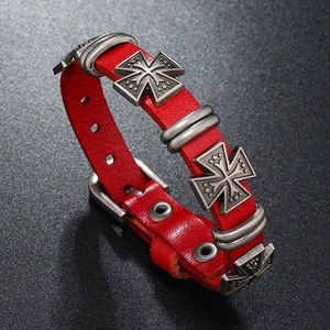 Dettaglio macro di un bracciale punk in pelle rossa con borchie a croce e fibbia argento