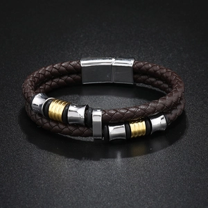 Détail du bracelet en cuir tressé marron avec perles argentées et dorées et fermoir magnétique