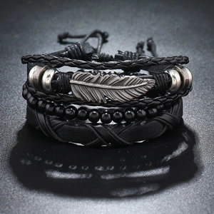 Macro view of multi-layer black leather bracelets with silver feather and woven details