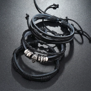 Detail of multi-layer black leather bracelets with silver skull and braided cord texture