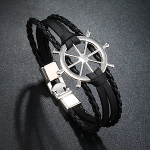 Detail of multi-layer leather bracelet with silver nautical helm charm and metal clasp