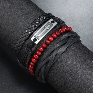 Vue macro de bracelets en cuir multicouches avec croix et perles rouges sur un support