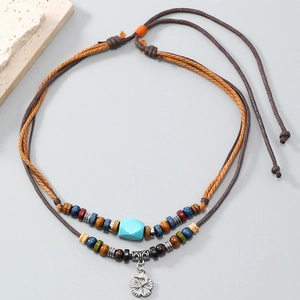 Detail of bohemian turquoise layered necklace with woven ropes and floral charm