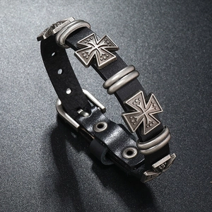 Dettaglio di un bracciale in pelle nera stile punk con croce d'argento e fibbia