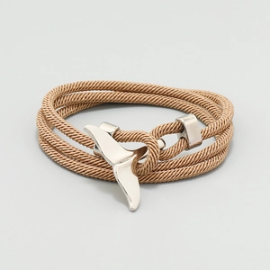 Detail of nautical whale tail charm on multi-layer light brown braided rope bracelet