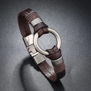 Détail d'un bracelet en cuir marron tressé multicouche avec anneau en métal argenté