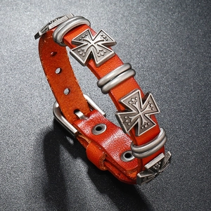 Dettaglio di un bracciale in pelle arancione in stile punk con croci metalliche argentate