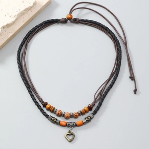Detail of bohemian layered woven necklace with wooden beads and vintage heart pendant