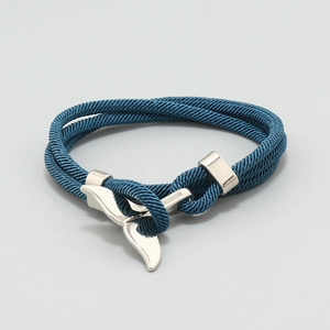 Close-up of a blue woven nautical bracelet featuring a silver whale tail metal clasp