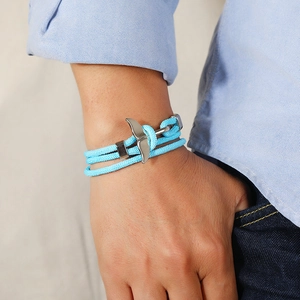 Close-up of light blue woven whale tail bracelet worn on wrist with ocean style aesthetic