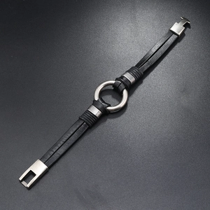Détail d'un bracelet multicouche en cuir noir tressé avec anneau et fermoir en métal argenté