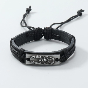 Macro detail of men's braided leather bracelet featuring vintage scorpion charm and cords