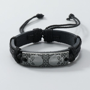 Detail of hand-woven black leather bracelet with carved metal skull charm and punk texture