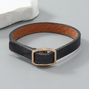 Detail eines minimalistischen schwarzen Lederarmbands mit goldener ovaler Metallschnalle