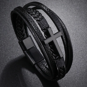 Detail of multilayered black leather bracelet with cross charm and magnetic clasp