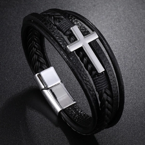 Macro shot of multi-layer black braided leather bracelet with silver cross and magnetic clasp