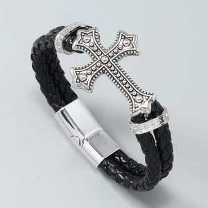 Detail of black braided leather bracelet with vintage silver cross and magnetic clasp