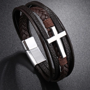 Detail of multi-layer leather bracelet featuring a silver cross and magnetic metal clasp