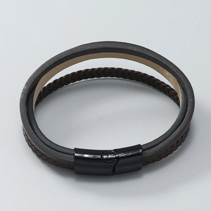 Detail of multi-layer brown braided leather bracelet with black magnetic clasp closure