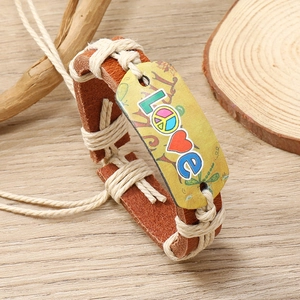 Close-up of a braided brown leather bracelet with Love and peace sign on a yellow plate