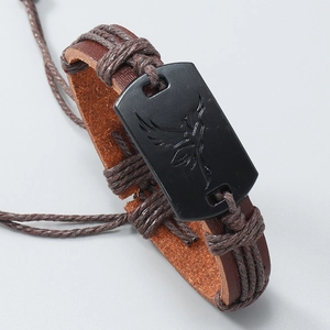 Detail of hand-woven leather bracelet with eagle engraved matte black metal plate