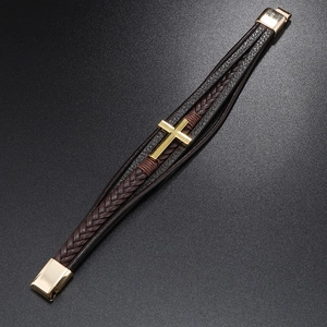 Macro view of men's multilayer braided leather bracelet with golden cross and magnetic clasp