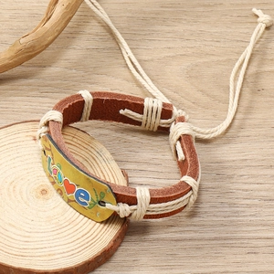 Handmade woven brown leather bracelet with yellow LOVE plaque on wood background