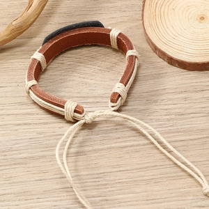 Detail of handmade braided leather bracelet with adjustable cord on wood background