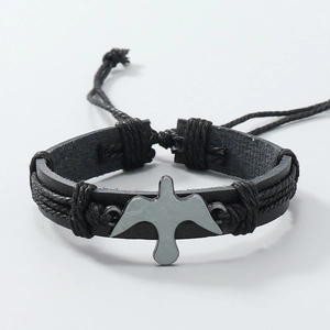 Detail of adjustable black leather braided bracelet with a silver bird charm