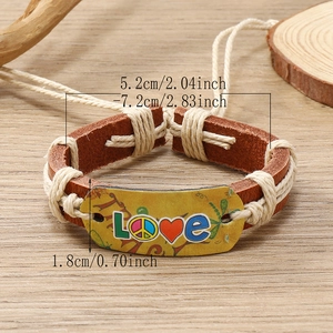 Handmade woven brown leather bracelet with LOVE printed tag on a natural wood surface
