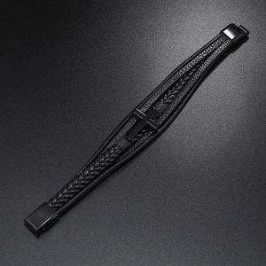 Macro detail of multi-layer braided black leather bracelet with metal cross and magnetic clasp