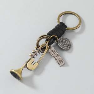 Détail du porte-clés trompette vintage avec plaque gravée et décoration en cuir noir