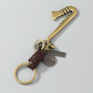Close-up of vintage saxophone keychain with woven leather and engraved metal tag