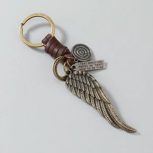 Detail of vintage feather pendant and engraved silver plate on leather keychain