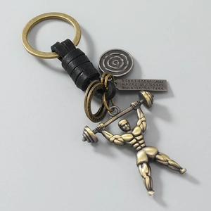 Detail of vintage bronze gym keychain with weightlifter charm and woven leather