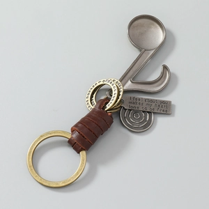 Close-up of vintage leather keychain with music note charms and engraved metal tags